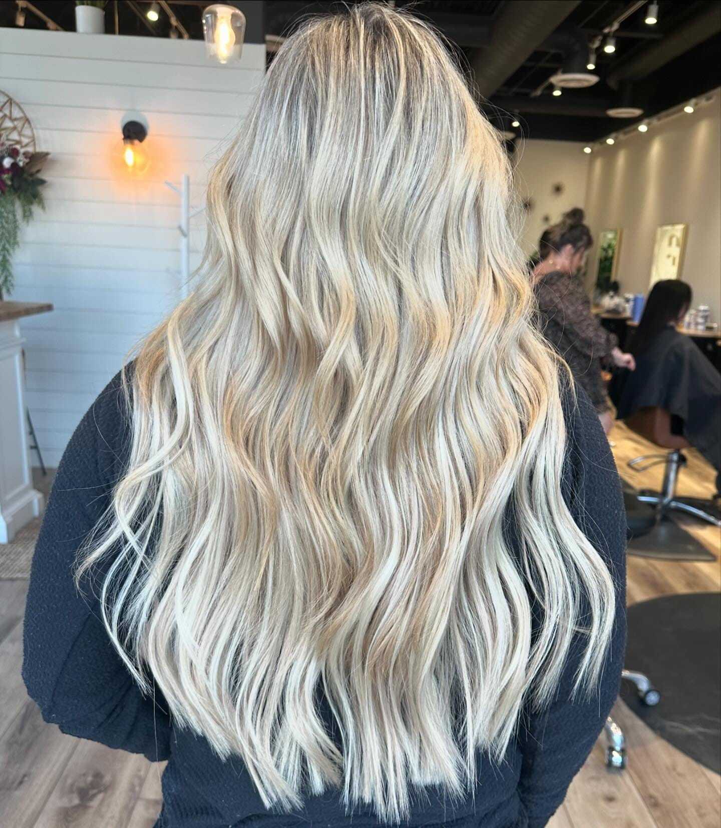 Woman with long, wavy blonde hair showcased in a salon.