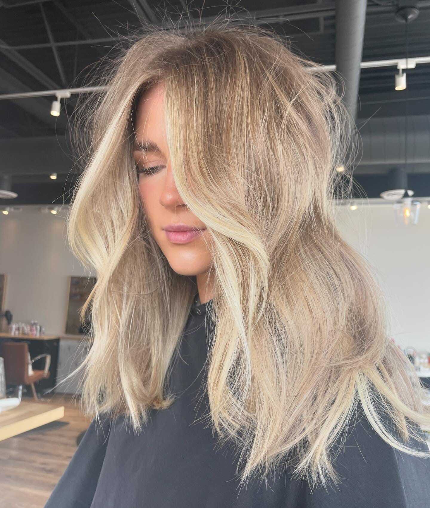 Woman with stylish balayage hair looking down.